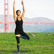 Woman doing outdoor yoga wearing slate polka-dotted compression calf sleeves